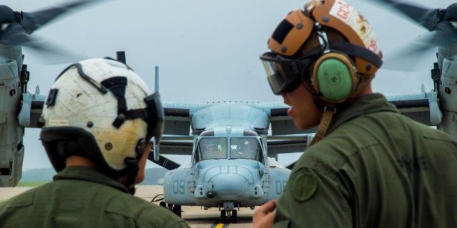 U.S. Marine Corps Cpl. Brandon Guico, a Marine Medium Tiltrotor Squadron 262 airframe aerial observer, and William Payne, a VMM-262 avionics technician, watch a MV-22 Osprey takeoff at Misawa Air Base, Japan last month.