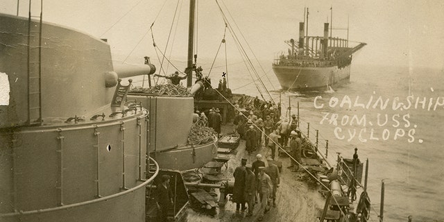 The USS Cyclops, in the background, transferring bags of coal with the USS South Carolina in 1914.