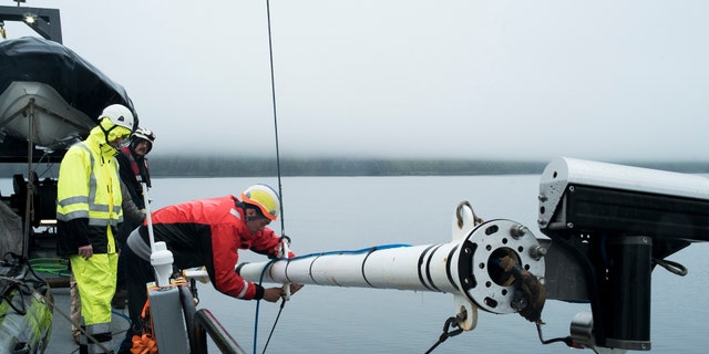 Project Engineer Andy Nager and archaeologist Andrew Pietruszka ready a pole-mounted multibeam unit for survey (Project Recover)