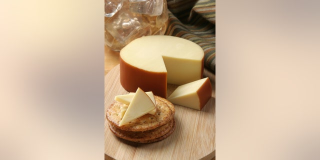 a wheel of smoked gouda cheese served with crackers