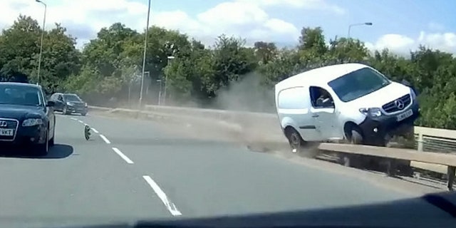 This video shows the see-it-to-believe-it moment when a van driver dices with death by grinding along the edge of a road bridge. See MASONS story MNVAN. The extraordinary footage of the white van grinding along the bridge rail Tony Hawk-style, going within inches of falling onto the dual carriageway below, happened in Burton-Upon-Trent, Staffordshire. The footage shows the van being forced to grind along the road rail and then the edge of the bridge itself by a car in the inside lane, which appears to make a late break for the A38 slip road. The footage was filmed by driving instructor Ian Stinchcombe, whose student was on her test at the time.