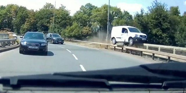 This video shows the see-it-to-believe-it moment when a van driver dices with death by grinding along the edge of a road bridge. See MASONS story MNVAN. The extraordinary footage of the white van grinding along the bridge rail Tony Hawk-style, going within inches of falling onto the dual carriageway below, happened in Burton-Upon-Trent, Staffordshire. The footage shows the van being forced to grind along the road rail and then the edge of the bridge itself by a car in the inside lane, which appears to make a late break for the A38 slip road. The footage was filmed by driving instructor Ian Stinchcombe, whose student was on her test at the time.