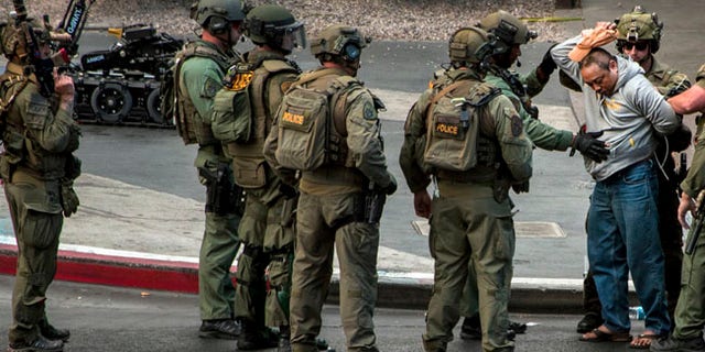 A suspect surrenders to SWAT officers after being barricaded for many hours on a bus after a fatal shooting in the vehicle earlier today which down the busy tourism corridor near the Cosmopolitan hotel-casino in Las Vegas, Saturday, March 25, 2017. Las Vegas Police officer Larry Hadfield said just before 3:30 p.m. that the man had a handgun and surrendered without incident. (L.E. Baskow/Las Vegas Sun via AP)
