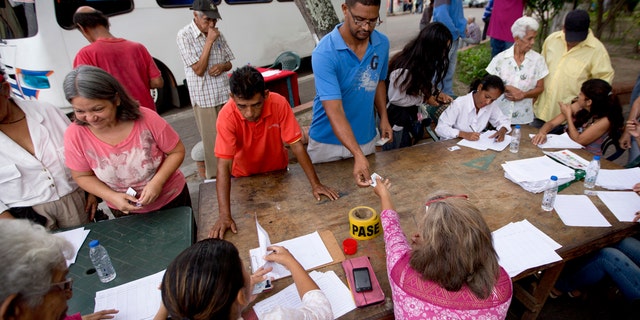 Voters register with members of the ruling United Socialist Party before proceeding to a polling post to vote in presidential elections in Valencia, Venezuela, Sunday, May 20, 2018.