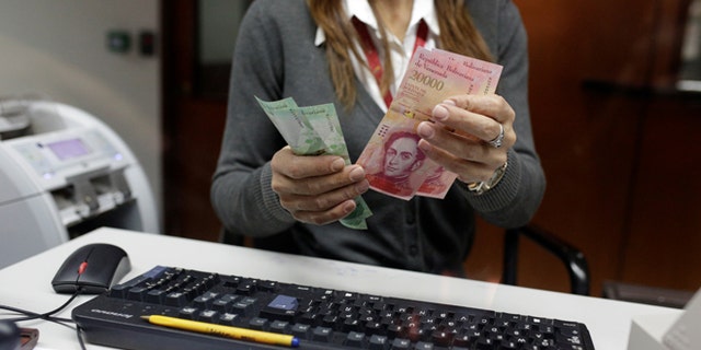 A bank teller counts bolivar banknotes at a Banco de Venezuela branch in Caracas, Venezuela January 16, 2017. REUTERS/Marco Bello - RTSVRHG
