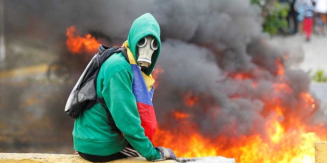Demonstrator sits next to a fire barricade on a street during a rally against Venezuela's President Nicolas Maduro in Caracas, Venezuela April 24, 2017. REUTERS/Christian Veron - RTS13RH3