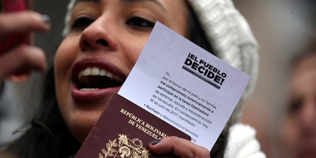 A Venezuelan woman shows her passport and a ballot certificate after casting her vote during an unofficial plebiscite against President Nicolas Maduro's government in Buenos Aires, Argentina, July 16, 2017. REUTERS/Marcos Brindicci - RC1C40A2CCC0