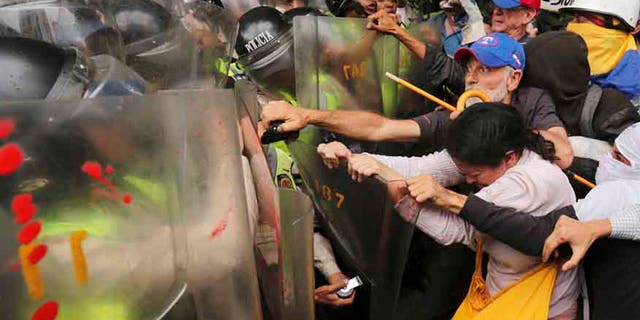 Anti-government protesters scuffle with police blocking older Venezuelans from marching to the Ombudsman's Office in protest of President Nicolás Maduro in Caracas, Venezuela, Friday, May 12, 2017.
