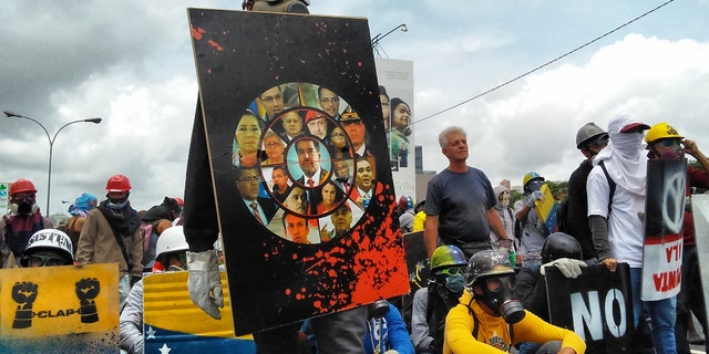 Young man observes the security forces with a shield that has the faces of high government officials.