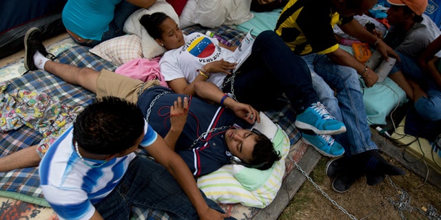 April 29, 2014: Students lie on a sidewalk chained to a nearby tree in protest against Venezuela's President Nicolas Maduro outside the UN headquarters in Caracas.