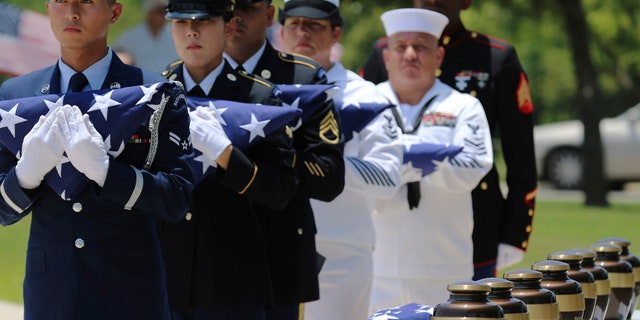 In this Friday, June 1, 2018 photo, military service members with the Armed Services Honor Guard prepare to present folded flags as Fort Sam Houston National Cemetery and the Missing In America Project conduct a military burial service for the cremated remains of eight unclaimed veterans in San Antonio.