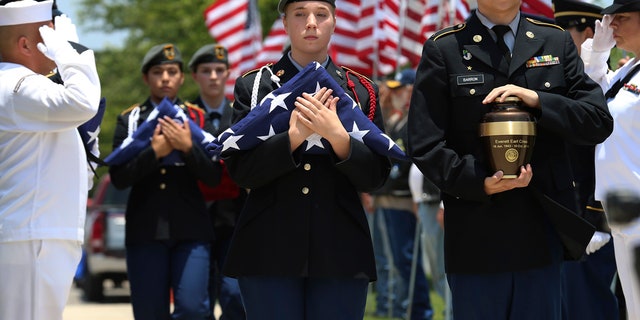 In this Friday, June 1, 2018 photo, MacArthur Junior ROTC students Michael Barron, right, and Grace Conger carry the cremated remains of veteran Everett Earl Criss as Fort Sam Houston National Cemetery and the Missing In America Project conduct a military burial service for the cremated remains of eight unclaimed veterans in San Antonio, Texas.