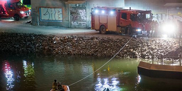 Divers and rescue service personnel search for the victims of the deadly car crash in the canal under the E4 highway bridge in Sodertalje, Sweden, late Saturday, Feb.13, 2016.  (Johan Nilsson/TT News Agency via AP)