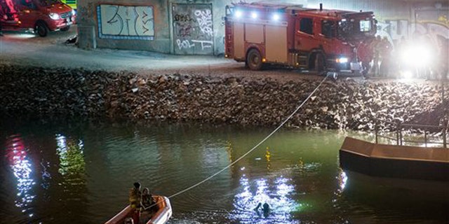 Divers and rescue service personnel search for the victims of the deadly car crash in the canal under the E4 highway bridge in Sodertalje, Sweden, late Saturday, Feb.13, 2016. (Johan Nilsson/TT News Agency via AP)