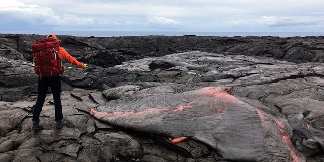 A geologists takes samples from the Kīlauea volcano, which is the youngest and southeastern most volcano on the Island of Hawai. See Masons copy MNVOLCANO: These fearless geologists have been captured while carryinging out one of the the most dangerous jobs in the world - collecting lava from inside firey volcanoes. The workers can be seen in a series of captivating images going about their risky everyday work at the summit of live volcanoes in Hawaii. Their jobs are crucial to help gather information and understand patterns in volcanic activity.