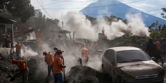 Rescue workers remove piles of ash spewed by the Volcan de Fuego, or "Volcano of Fire," eruption, in El Rodeo, Guatemala, Wednesday, June 6, 2018. Wednesday morning rescuers were concerned about possible dangers posed not only by more volcanic flows but also rain. Authorities have said the window is closing on the chances of finding anyone else alive in the devastation. (AP Photo/Rodrigo Abd)