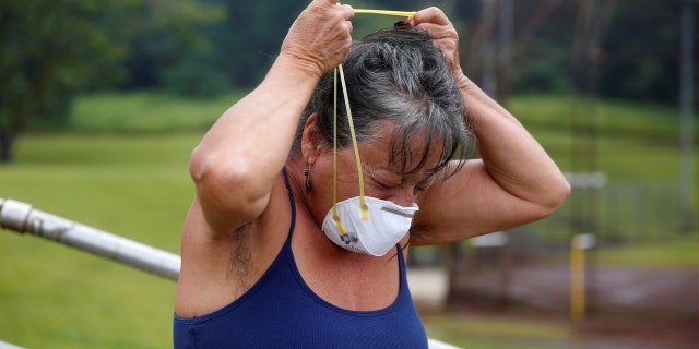 Laura Rillamas, of Orchidland, puts on a dust mask to protect herself from volcanic emissions in Keaau during ongoing eruptions of the Kilauea Volcano in Hawaii.