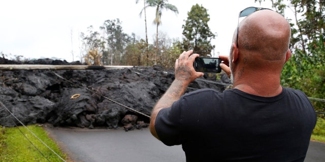 A resident of the Leilani Estates subdivision takes photos of a lava flow near his home.