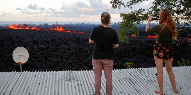 Jolon Clinton, 15, left, and her sister, Halcy, 17, take photos of a fissure near their home on the outskirts of Pahoa.