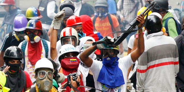 An anti-government demonstrator shows a shotgun taken from security forces during clashes in Caracas, Venezuela, Monday, May 8, 2017,