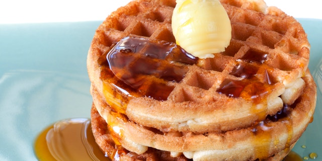 Stack of waffles with maple syrup and butter.
