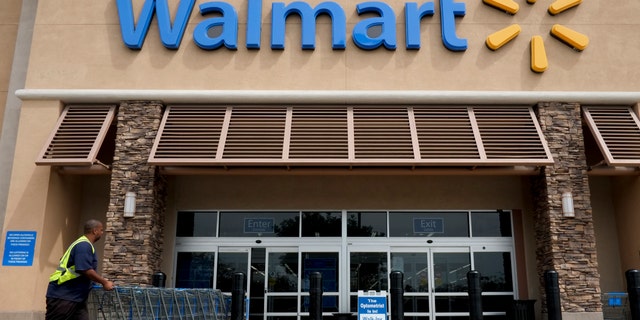 FILE - In this May 9, 2013, file photo, a worker pushes shopping carts in front of a Wal-Mart store in La Habra, Calif.