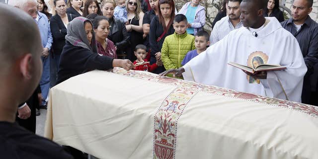 Feb. 25, 2015: Agapita Montes-Rivera, left, places a crucifix on the coffin of her son, Antonio Zambrano-Montes during his funeral service conducted by Rev. Lutakome Nsubuga.