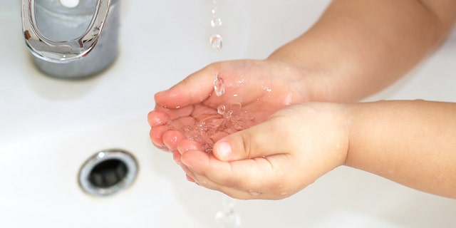 Clean water from a water valve flows into a child's palms. If your home has a private well, it needs to be tested once a year to ensure protection, say professionals.