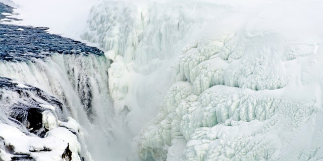 Gullfoss, a waterfall on the Hvita River in Iceland, in winter (March). Fantastic ice formations form between riverlets of flowing water and on opposite bank.