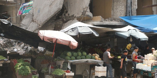 Vendors wait for customers near their stalls erected in front of damaged buildings during the holy month of Ramadan in the rebel held area of Aleppo's al-Shaar district, Syria, June 15, 2016. REUTERS/Abdalrhman Ismail - RTX2GDRZ
