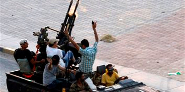 Libyan rebels fire into the air in the Bab El Bahrah district in Tripoli, Tuesday, Aug. 23, 2011. Hundreds of Libyan rebels blasted through the green gates of Moammar Gadhafi's Bab al-Aziziya compound in Tripoli Tuesday after five hours of intense fighting around it.