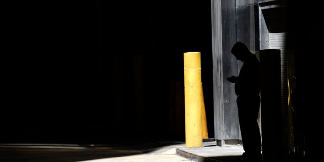 FILE- In this June 6, 2017, file photo, a man checks his phone in an alley in downtown Chicago. A security researcher says a website flaw at a U.S. company could have allowed anyone to pinpoint the location of nearly any cellphone in the United States. The lapse at LocationSmart, a company that gathers real-time data on cellular wireless devices, is the latest to highlight how little protection consumers have from trafficking in data about their location. (AP Photo/G-Jun Yam, File)