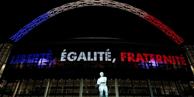 The statue of England soccer legend Bobby Moore stands out side a Wembley Stadium that bears the French nationals colours before the international friendly soccer match between England and France in London, Tuesday, Nov. 17, 2015. France is playing England at Wembley on Tuesday after the countries decided the match should go ahead despite the deadly attacks in Paris last Friday night which killed scores of people. (AP Photo/Alastair Grant)
