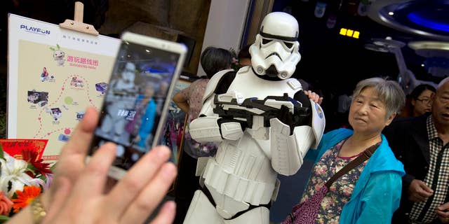 A Chinese woman poses for a photo with a worker dressed in a storm trooper costume at the Wanda Mall outside of the Wanda Cultural Tourism City in Nanchang in southeastern China's Jiangxi province, Saturday, May 28, 2016. The Walt Disney Co. owns the rights to Lucas Film and associated properties.