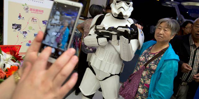 A Chinese woman poses for a photo with a worker dressed in a storm trooper costume at the Wanda Mall outside of the Wanda Cultural Tourism City in Nanchang in southeastern China's Jiangxi province, Saturday, May 28, 2016. The Walt Disney Co. owns the rights to Lucas Film and associated properties.
