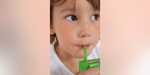 Young boy drinking juice box indoors