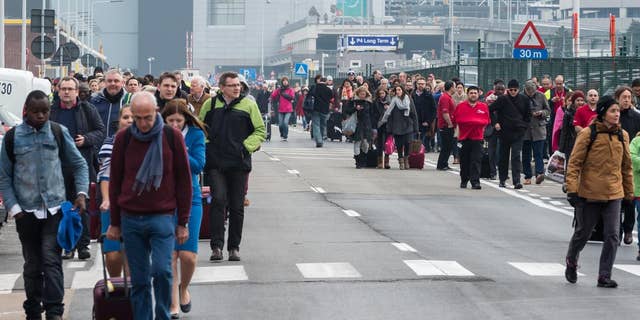 People walk away from Brussels airport after explosions rocked the facility in Brussels, Belgium Tuesday March 22, 2016.