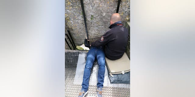 A woman bends backward to kiss the famed Blarney Stone.