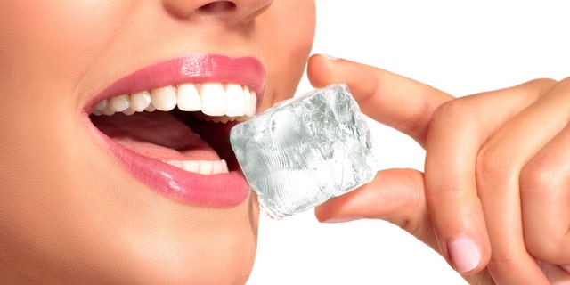 Closeup of beautiful woman biting an ice cube on white