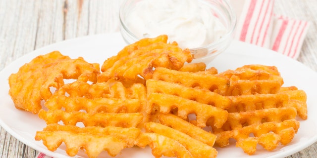 Potato waffle fries with a sour cream and chive dip - studio shot