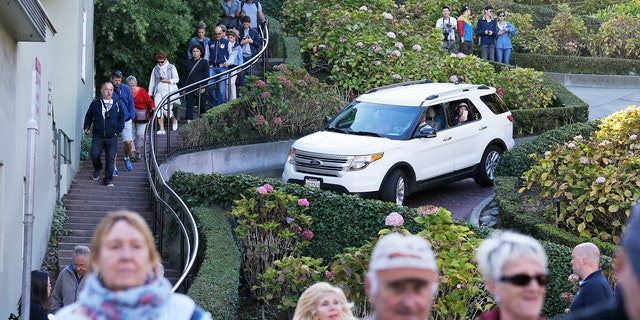 Tourists make their way down Lombard Street, also known as the "most crooked street" in San Francisco. The crooked block has become so chaotic that the city of San Francisco is considering solutions as drastic as banning cars or requiring timed reservations.