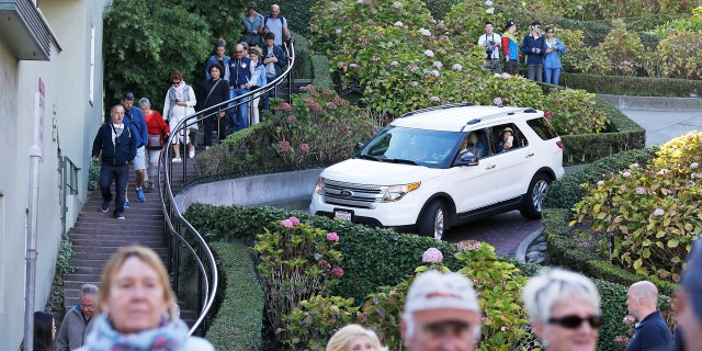 Tourists make their way down Lombard Street, also known as the "most crooked street" in San Francisco. The crooked block has become so chaotic that the city of San Francisco is considering solutions as drastic as banning cars or requiring timed reservations.