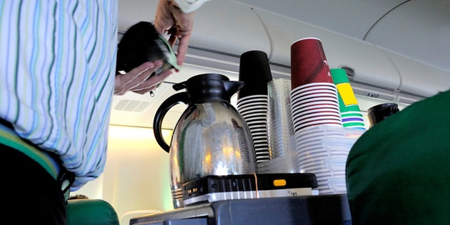 Steward pouring coffee in the cabin of an airplane