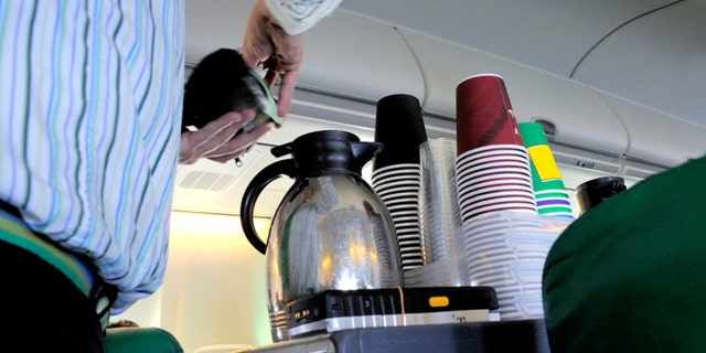 Steward pouring coffee in the cabin of an airplane