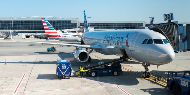 New York, USA - July 10, 2015: An America Airlines plane sitting at gate 39 at JFK airport late in the day as ground crew finish up before take off.