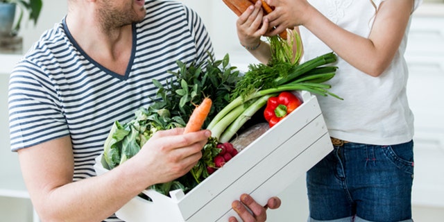 Father and daughter with vegetable box in kitchen