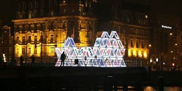 People look at a light sculpture called, "House of Cards," by OGE Creative Group, from Israel, near Central Station in Amsterdam. The sculpture is a playful part of the Amsterdam Light Festival which opened Nov. 27, 2014, with the aim of bringing a little illumination and color into the gloomy days and nights of winter that are settling over the Dutch capital.