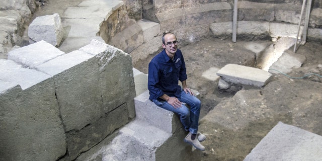 Dr Joe Uziel of the Israel Antiquities Authority, sitting on the steps of the theater structure. (Photograph: Yaniv Berman, courtesy of the Israel Antiquities Authority)