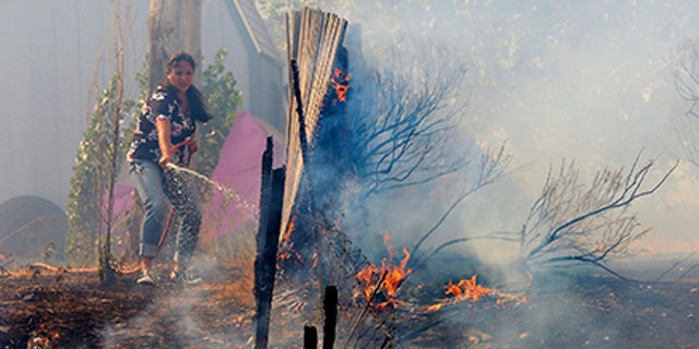A homeowner tries to douse a wildfire near Weber Canyon in Utah Tuesday.
