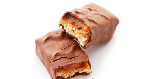 Tasty chocolate bar split in two pieces. Delicious caramel cream and peanuts inside. White background.